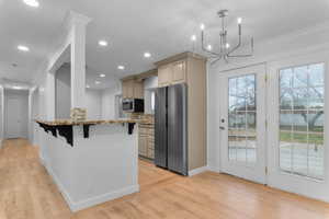 Kitchen featuring a breakfast bar, light stone counters, appliances with stainless steel finishes, crown molding, and backsplash