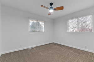 Empty room with dark colored carpet and ceiling fan