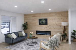 Living area with wood walls, wood finished floors, an accent wall, a glass covered fireplace, and recessed lighting