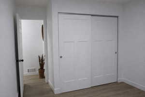 Unfurnished bedroom with a closet and dark wood-style flooring