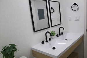 Bathroom featuring a textured wall, electric panel, and vanity