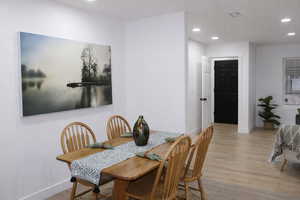 Dining area with light wood finished floors and recessed lighting