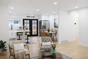 Living area with french doors, recessed lighting, light wood-type flooring, and arched walkways