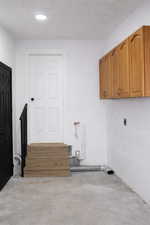 Laundry room featuring unfinished concrete floors and cabinet space
