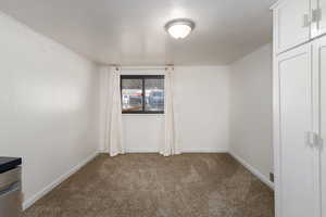 Unfurnished room with dark colored carpet and baseboards