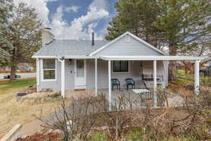 Bungalow-style house with roof with shingles, a patio area, and a chimney