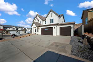 Modern farmhouse featuring stucco siding, driveway, a garage, a residential view, and a tiled roof