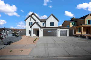 Modern inspired farmhouse with concrete driveway, stucco siding, and an attached garage