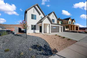 View of front facade with driveway, stucco siding, a garage, and covered porch