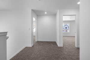 Hallway with dark colored carpet and recessed lighting