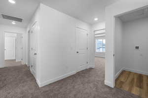 Corridor with dark carpet and recessed lighting