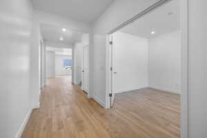 Hallway featuring light wood finished floors and recessed lighting