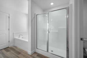 Full bathroom featuring a shower stall, a garden tub, and light wood-style floors