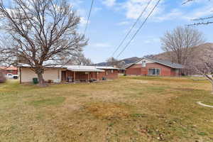 Back of property with a patio, a lawn, and a mountain view