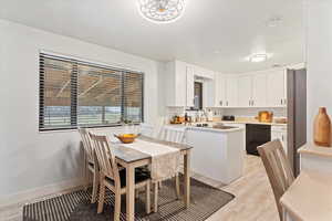 Kitchen with light countertops, white cabinetry, black dishwasher, and light wood finished floors