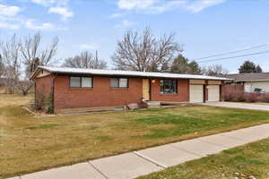 Ranch-style home featuring brick siding, a front lawn, a metal roof, and concrete driveway
