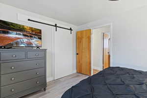 Bedroom with a barn door and light wood-style floors