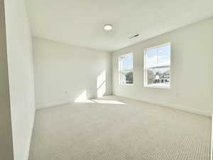 Carpeted spare room featuring a textured ceiling and baseboards