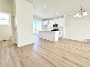 Kitchen featuring white cabinets, open floor plan, hanging light fixtures, a kitchen island with sink, and recessed lighting