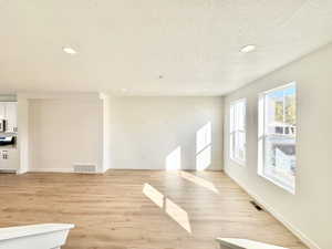 Unfurnished living room with recessed lighting, a textured ceiling, and light wood-style floors