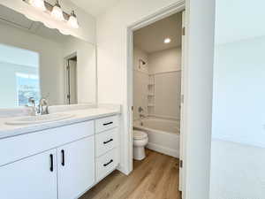 Bathroom with vanity, shower / washtub combination, and light wood-style flooring