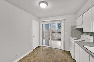 Kitchen featuring white cabinets, white electric range, light countertops, and under cabinet range hood