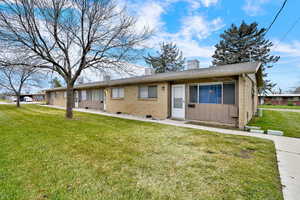 Ranch-style house featuring a front yard, a chimney, brick siding, a shingled roof, and board and batten siding