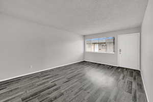 Empty room featuring a textured ceiling and dark wood-type flooring