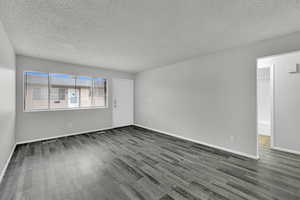 Unfurnished room featuring a textured ceiling and dark wood-style flooring