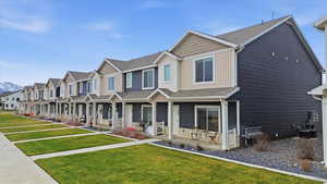 View of front facade with a porch, a residential view, board and batten siding, and a front lawn