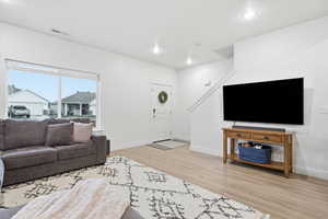Living area with light wood-type flooring and recessed lighting