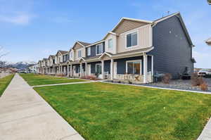 View of front of property featuring a porch, board and batten siding, a residential view, and a front lawn
