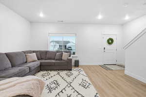 Living room featuring light wood finished floors, recessed lighting, and stairway