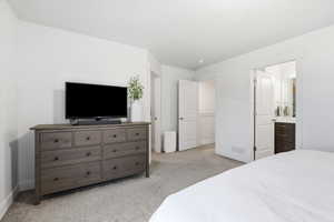 Bedroom featuring light carpet and ensuite bath