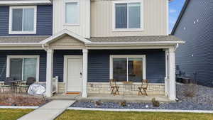View of front of home featuring a porch, a shingled roof, and stone siding