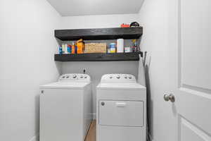 Washroom with washing machine and clothes dryer and light wood finished floors