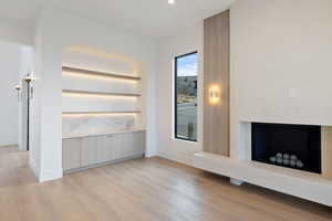 Main floor living room featuring light wood-type flooring, a fireplace with raised hearth, and recessed lighting