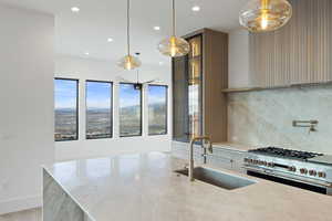 Kitchen with light stone countertops, double oven range, tasteful backsplash, hanging light fixtures, and modern cabinets