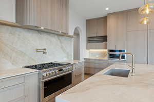 Kitchen featuring light stone counters, appliances with stainless steel finishes, open shelves, pendant lighting, and modern cabinets