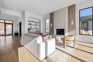 Living room featuring built in features, wood finished floors, recessed lighting, and a large fireplace