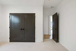 Bedroom featuring light carpet and a closet