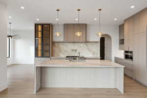 Kitchen featuring light stone counters, pendant lighting, modern cabinets, a large island, and recessed lighting