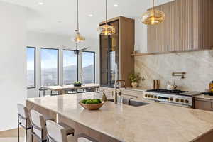 Kitchen featuring light stone counters, hanging light fixtures, a breakfast bar, double oven range, and a mountain view