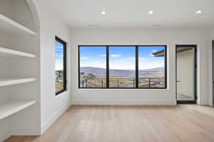 Primary bedroom with light wood finished floors, a mountain view, and recessed lighting