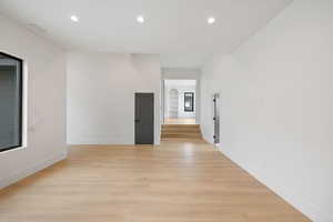 Upstairs living room with light wood-type flooring, recessed lighting, and arched walkways