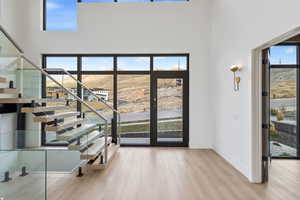 Foyer entrance featuring stairway, light wood-style floors, and a towering ceiling