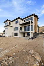 Rear view of property featuring stucco siding, a patio area, and a balcony