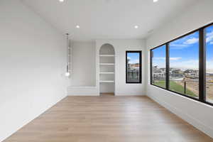 Primary bedroom with built in shelves, light wood finished floors, and recessed lighting