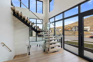 Stairway featuring healthy amount of natural light, wood finished floors, and a towering ceiling