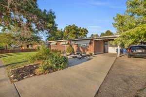 View of front facade with brick siding, an attached carport, and driveway